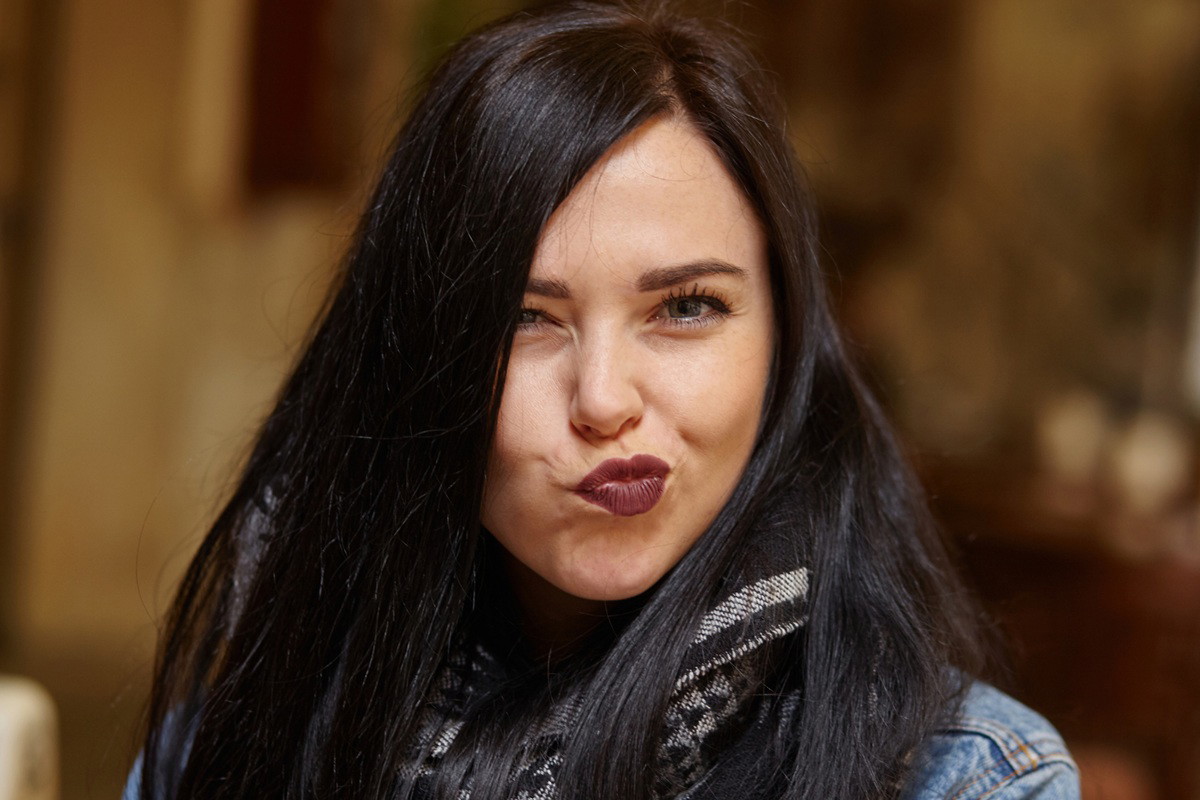 kobieta w wieku 30 plus z ciemnymi włosami robi zabawną minkę i jest zadowolona