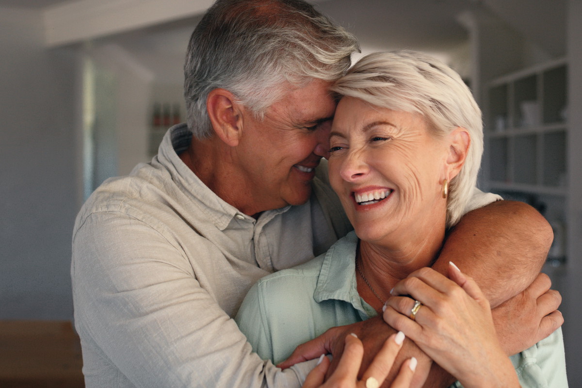 Home, hug and senior couple with love, funny and bonding together with happiness, trust and care. Laughing, old man or mature woman in house, embrace or relationship with marriage or smile with humor