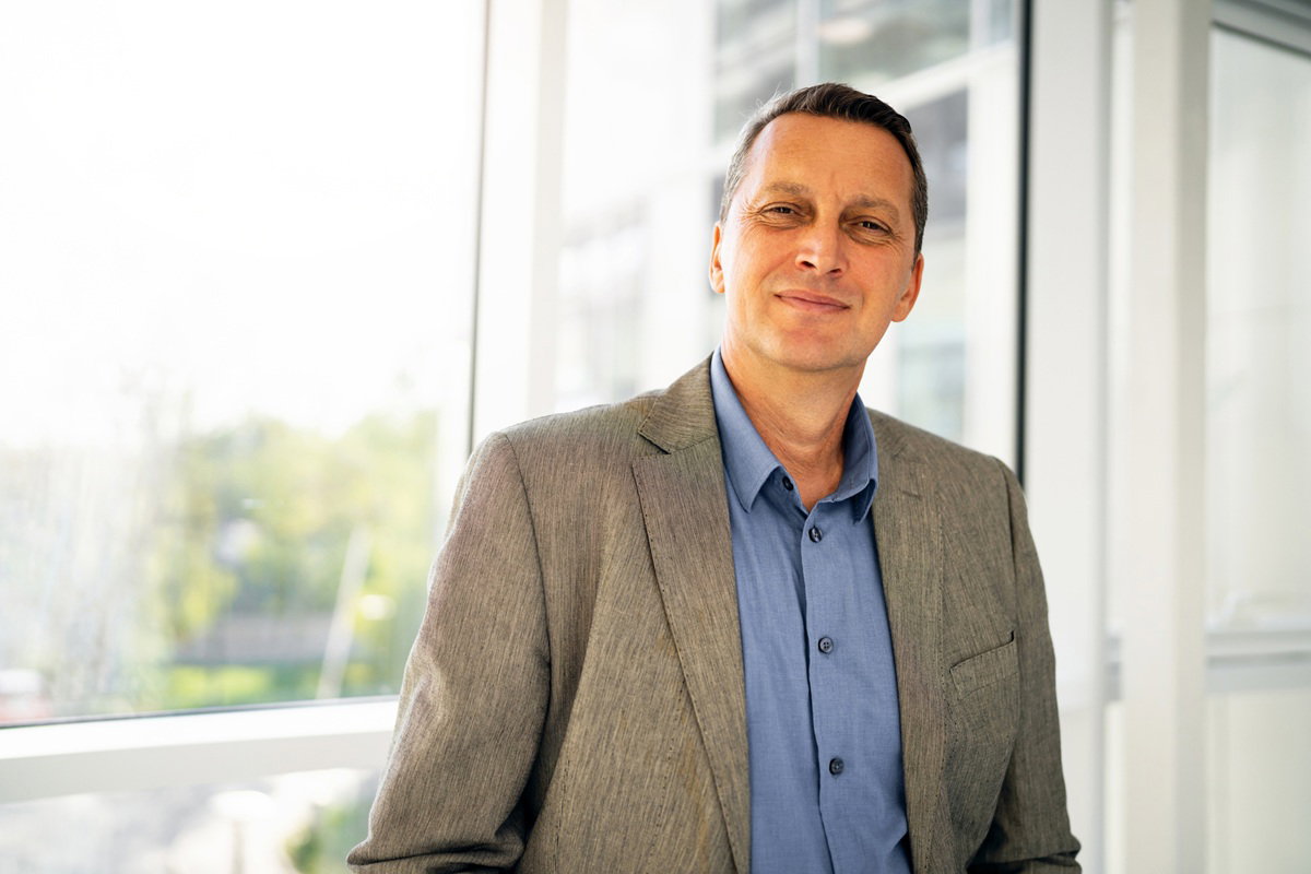 mężczyzna w wieku 40 plus stoi na tle okna marynarce zmęczony życiem i zamyślony