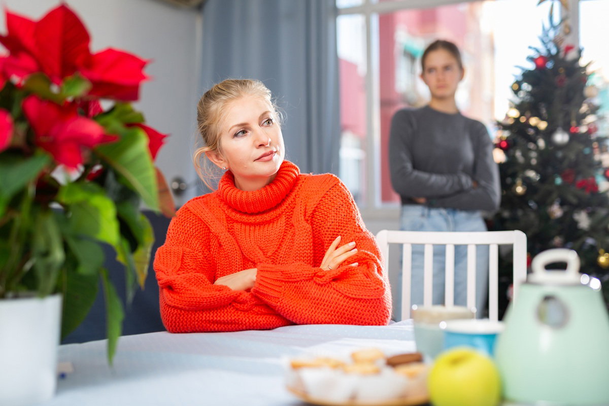 kobieta w wieku 40 plus w czerwonym swetrze siedzi zmartwiona przy stole