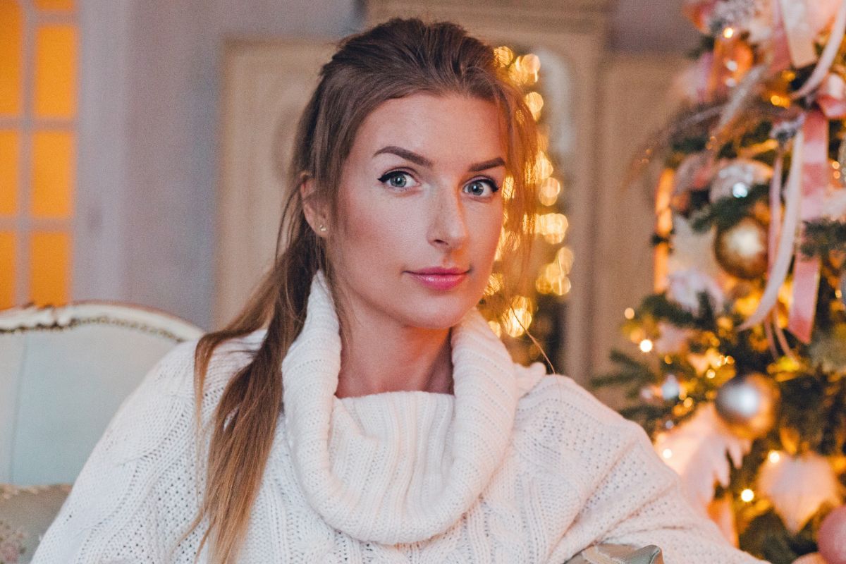 kobieta w białym swetrze przy choince