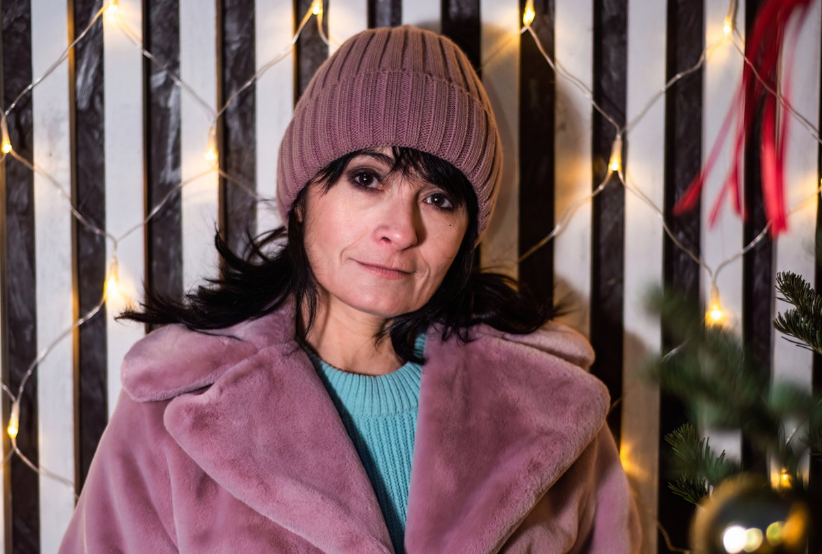 kobieta w wieku 50 plus w różowym futerku i czapce z zatroskaną miną