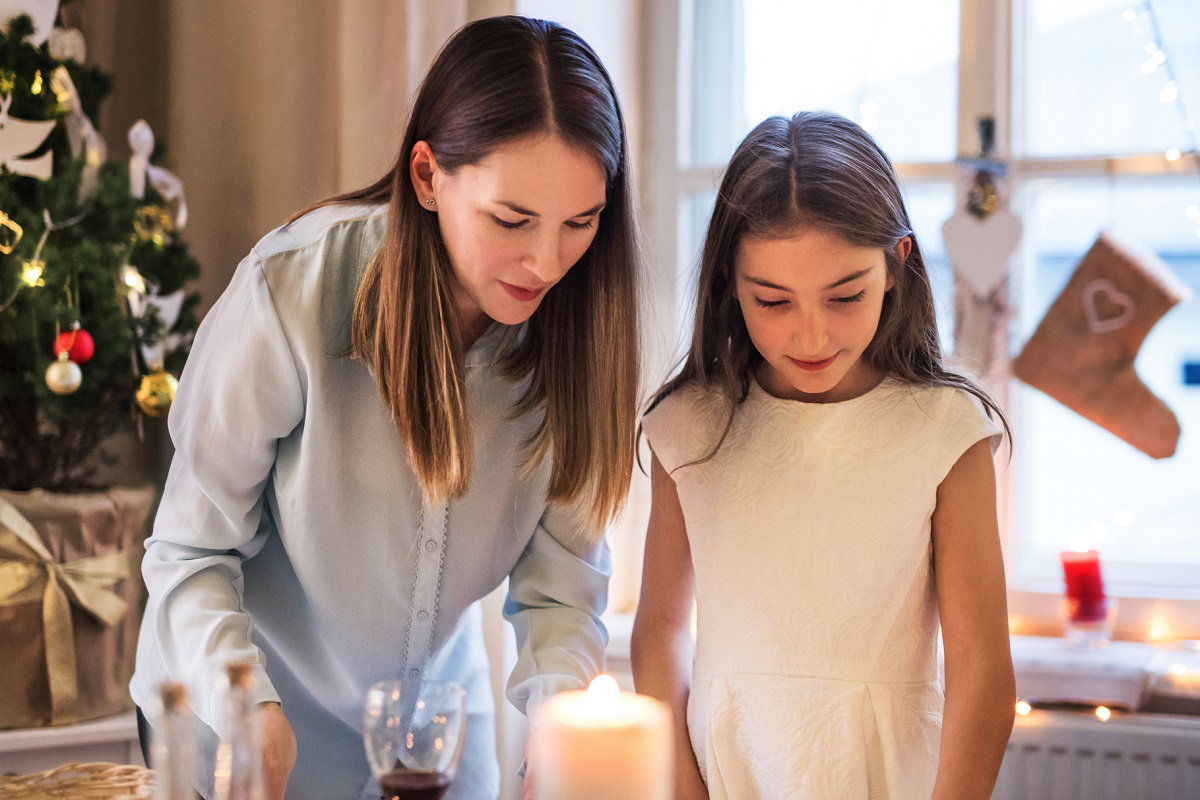 Portrait of mother with small daughter standing at Christmas indoors at home.