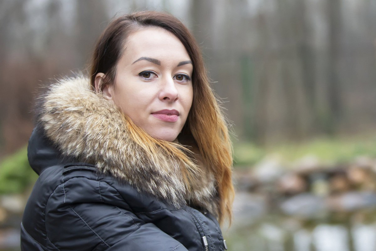 kobieta w wieku 30 plus w czarnej kurtce na łonie natury siedzi zamyślona