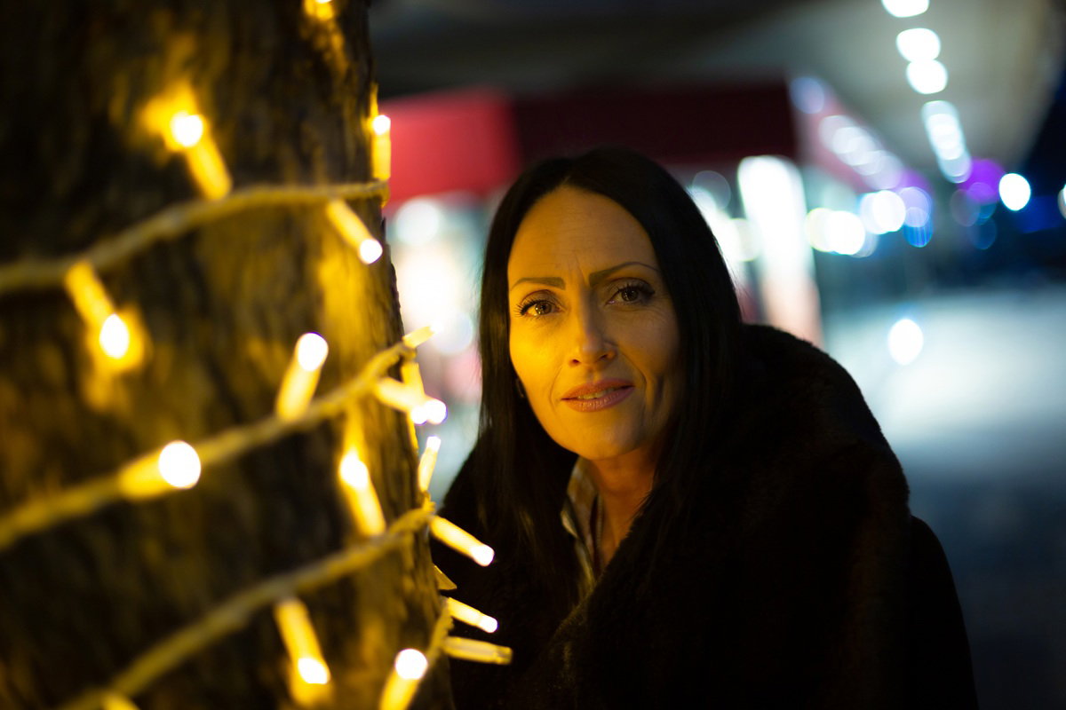 kobieta z ciemnymi włosami w wieku 40 plus stoi poważna wieczorową świąteczną porą