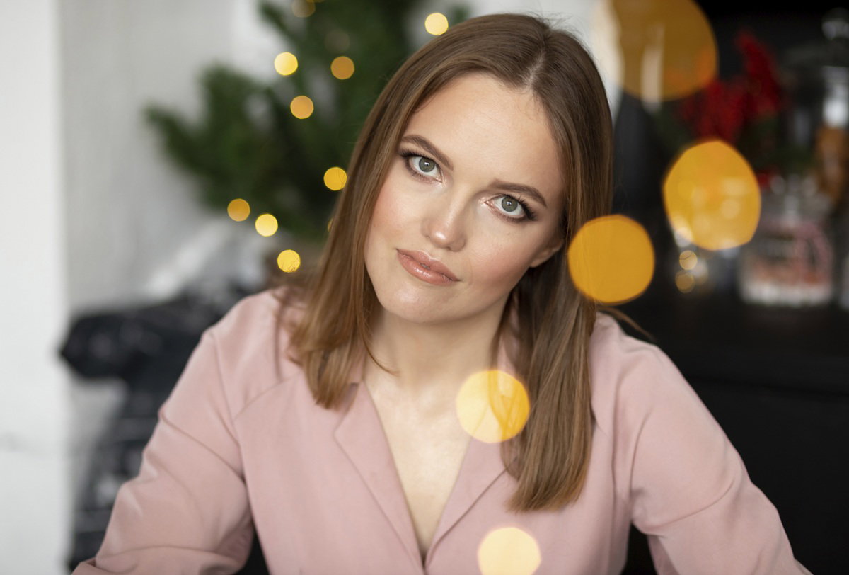 kobieta w wieku 30 plus siedzi na tle choinki z powątpiewającą miną