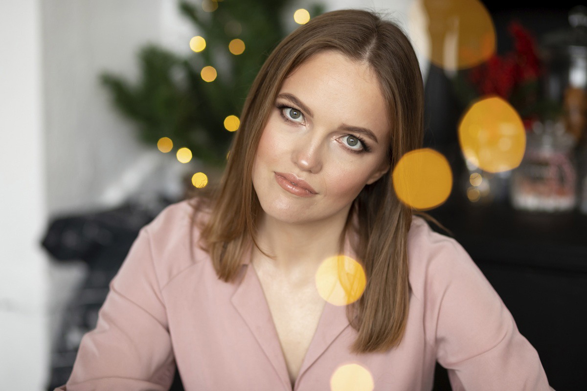 kobieta w wieku 30 plus siedzi na tle choinki z powątpiewającą miną