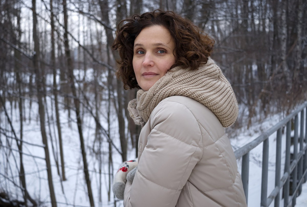 kobieta w beżowej kurtce w wieku 35 lat stoi na spacerze w zaśnieżonej scenerii z nadzieją w oczach