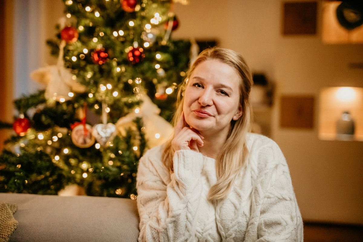 kobieta w wieku 35 plus w jasnym swetrze na tle choinki ma powątpiewającą minę