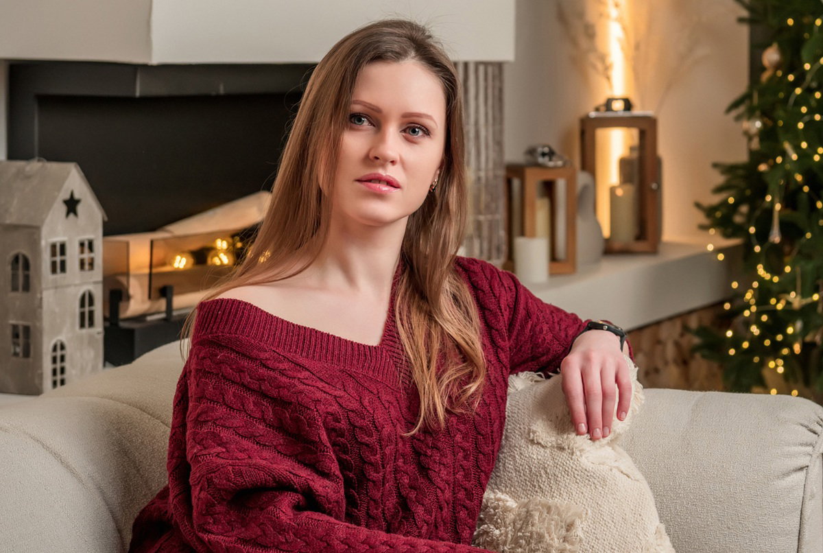 kobieta w wieku 30 plus siedzi w swetrze przy kominku zasmucona