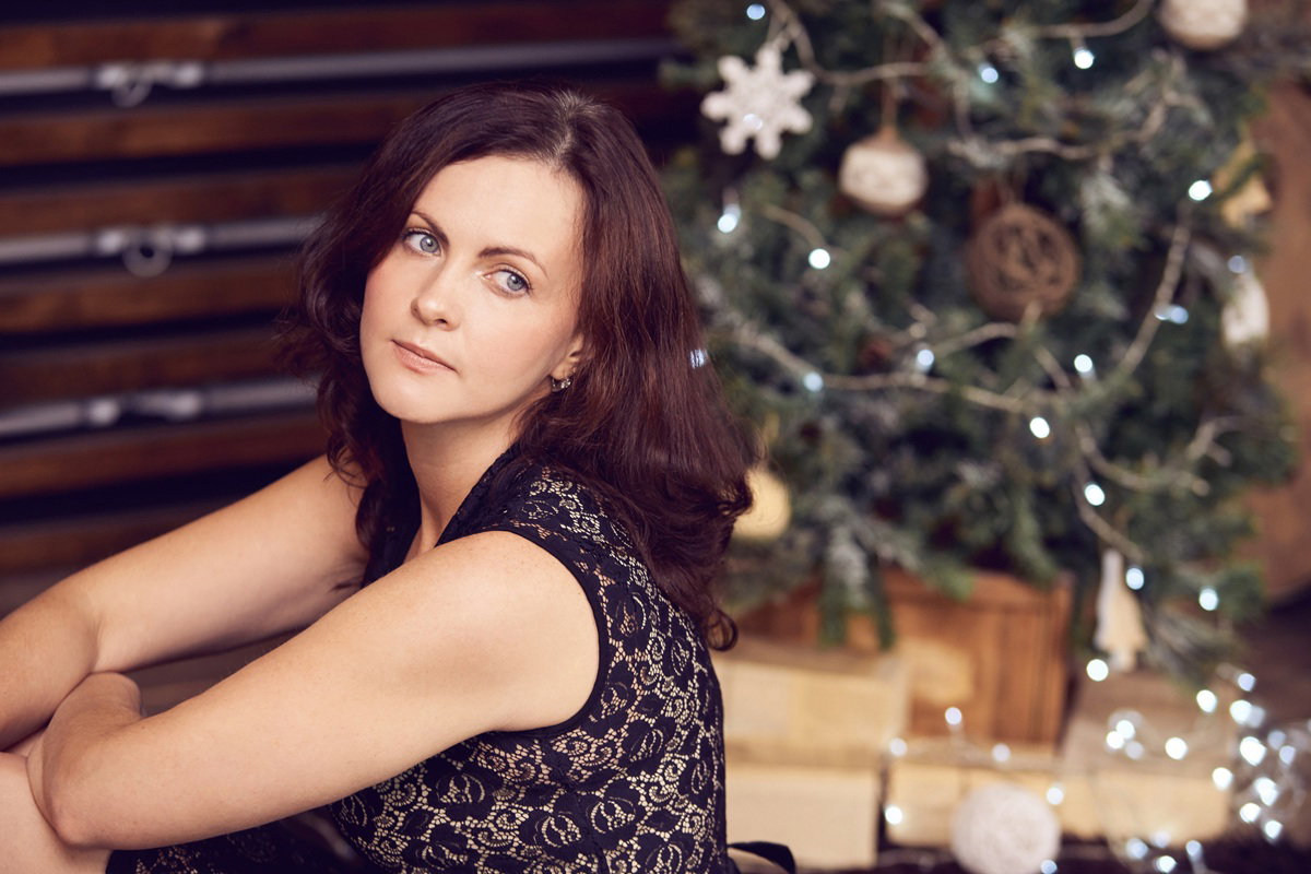 kobieta w wieku 35 plus siedzi smutna przy choince i zamyślona