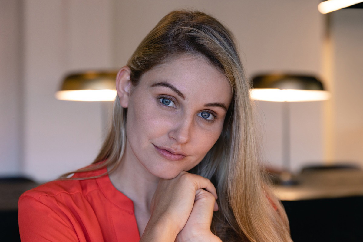 kobieta w wieku 25 plus blondynka w czerwonej bluzce stoi wewnątrz nieco zmieszana