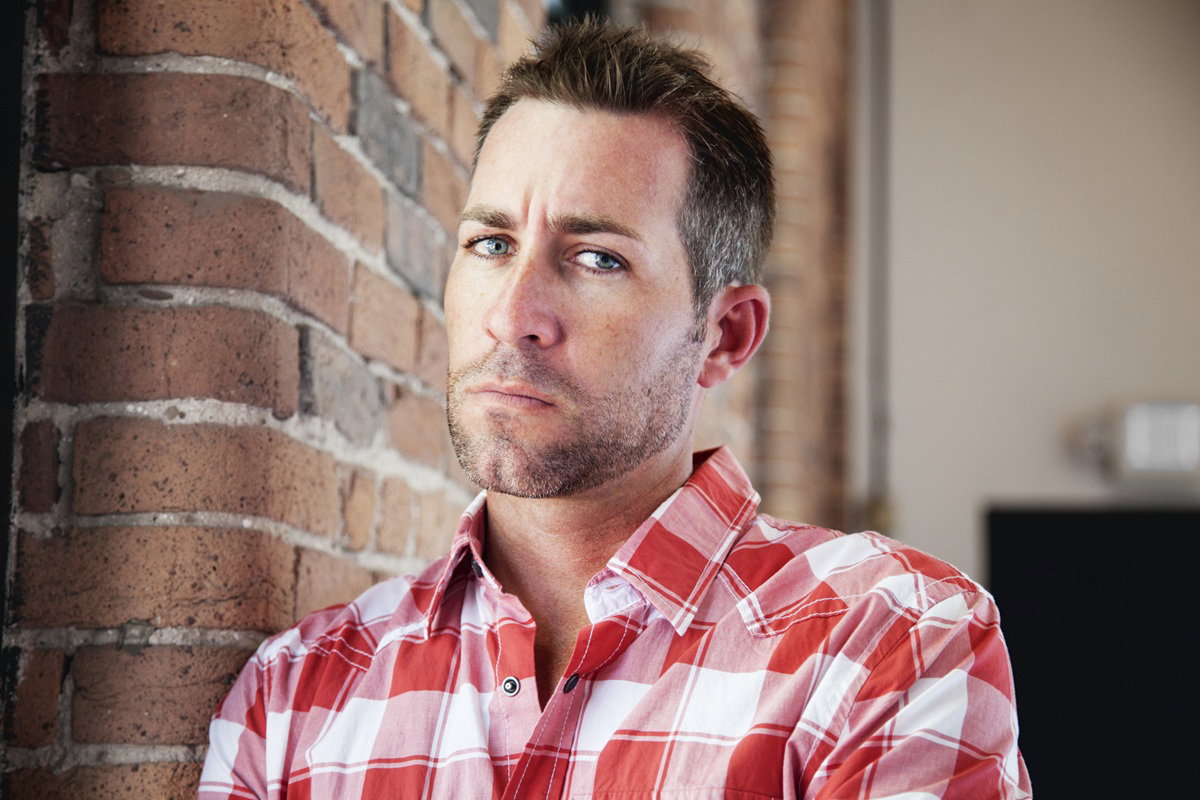 mężczyzna w wieku 30 plus z zarostem w koszuli w kratę ze smutnym spojrzeniem