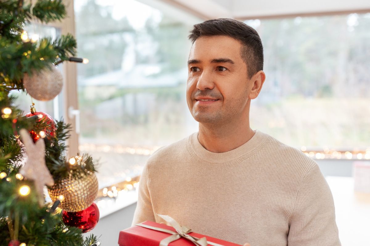 mężczyzna z prezentem pod choinkę