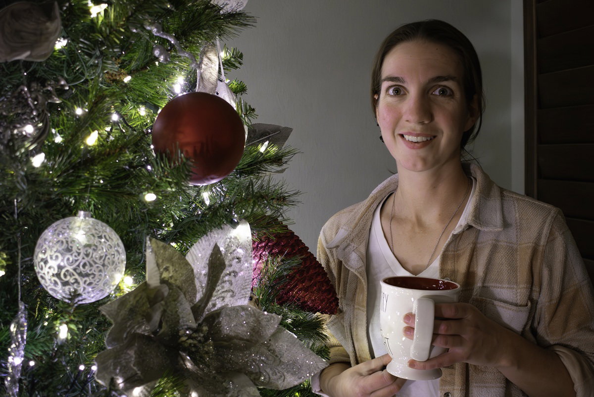kobieta w wieku 35 plus stoi przy choince lekko zadziwiona i zaskoczona