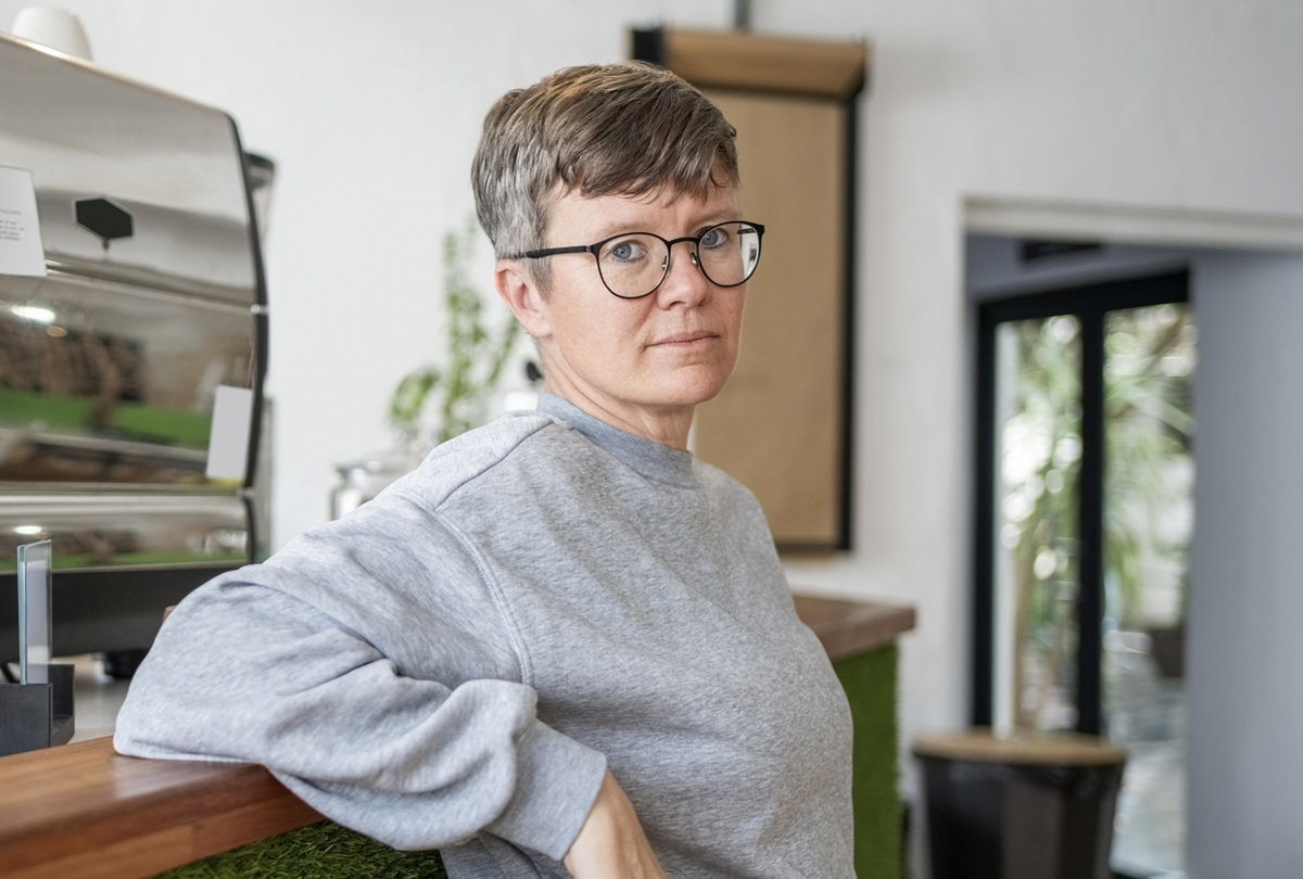 kobieta w wieku 40 plus w szarej bluzie stoi poważna w restauracji opierając się o kontuar