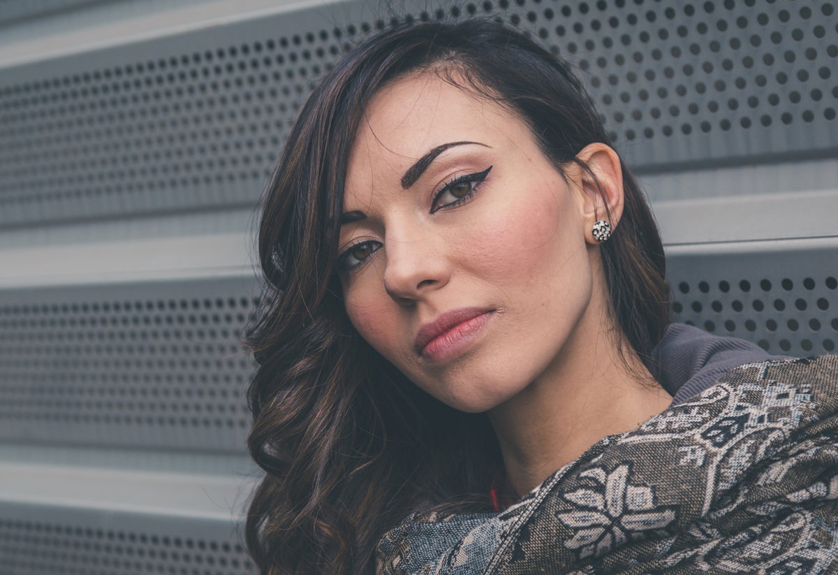 kobieta w wieku około 35 lat ze wzorzystym szalem na szyi stoi na zewnątrz zamyślona