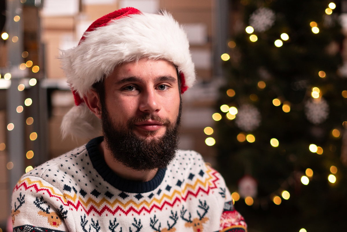 Portrait of male worker in busy modern warehouse working on laptop computer, Christmas sale concept
