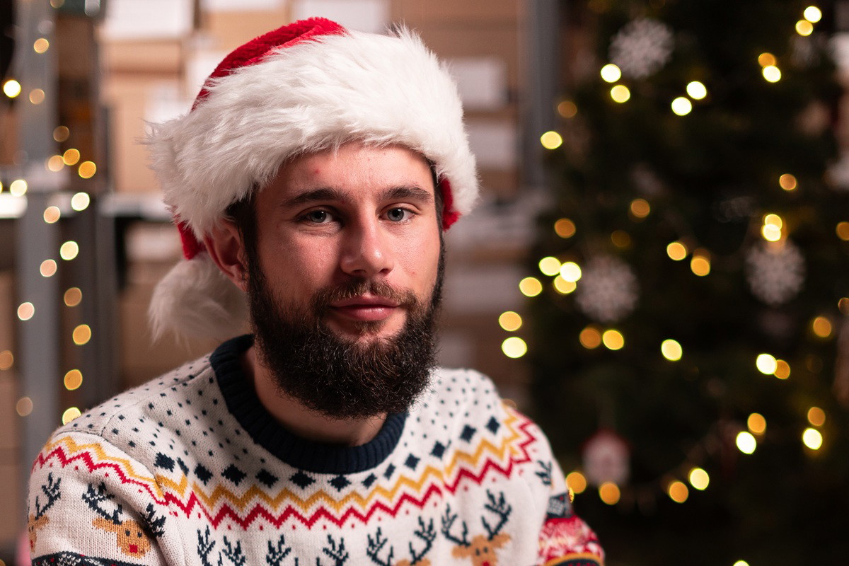 Portrait of male worker in busy modern warehouse working on laptop computer, Christmas sale concept