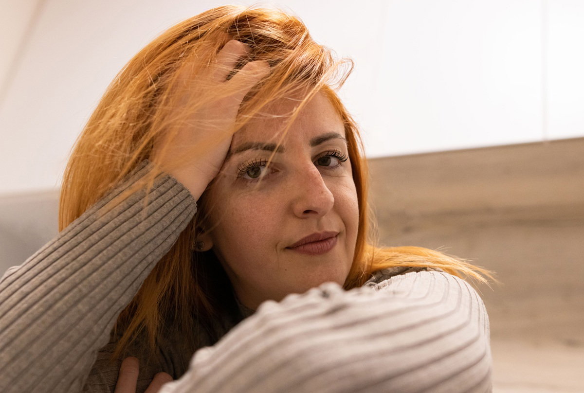 kobieta z rudymi włosami w wieku 35 plus siedzi zamyślona i wkurzona
