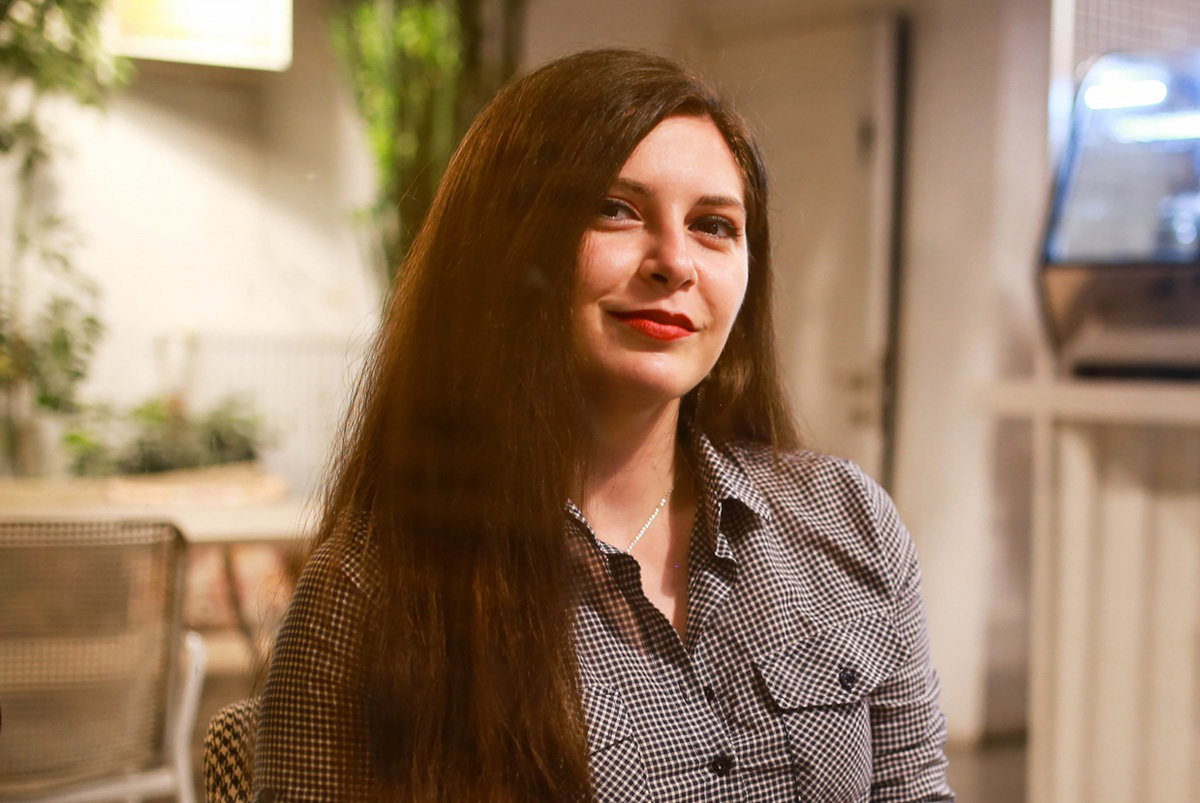 kobieta w wieku 30 plus z długimi włosami siedzi w kawiarni i lekko się uśmiecha