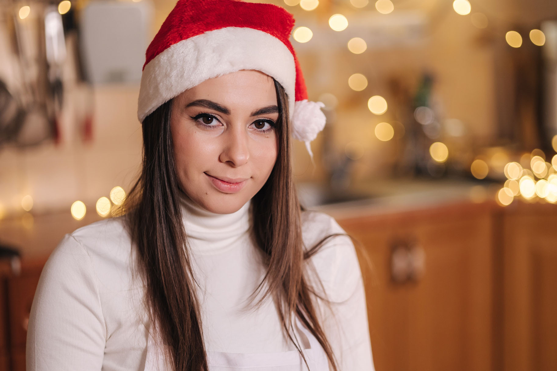 Portrait of attractive young mom in santa hat at kitchen. Christmas holidays