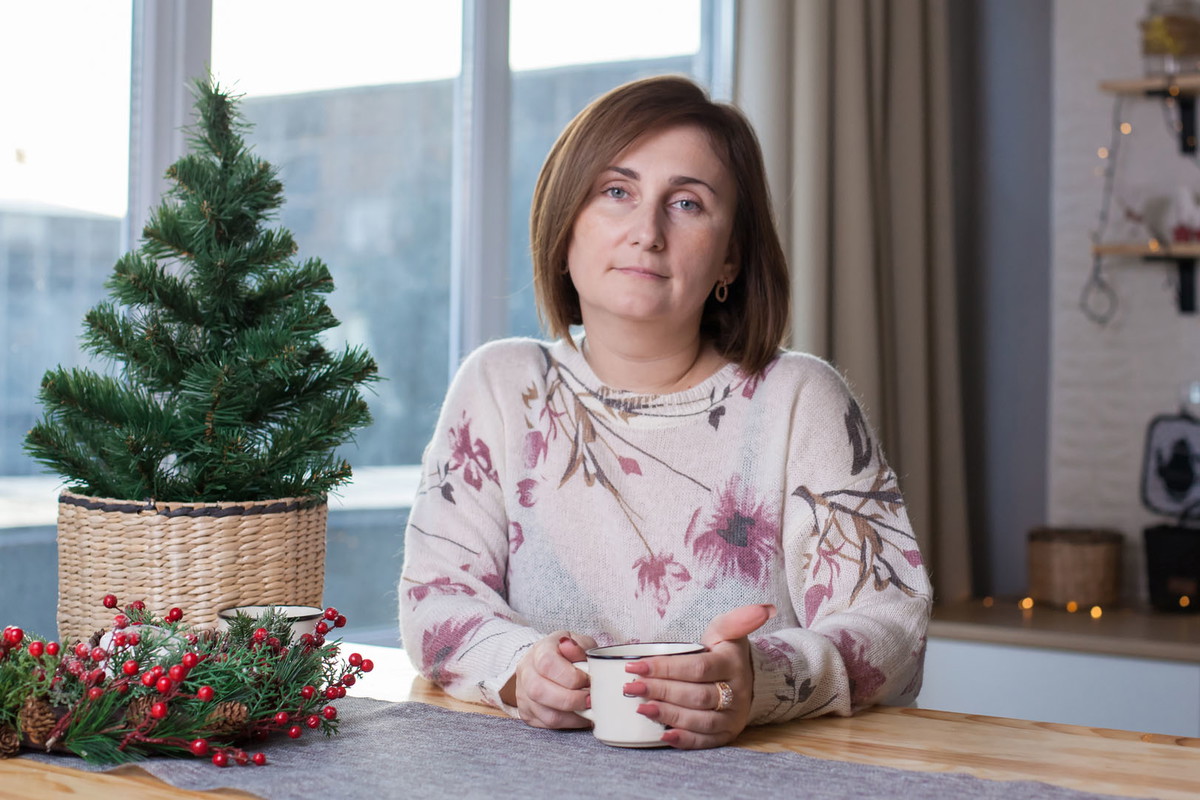 A woman sitting at a table and drinking tea in Christmas decorated room
