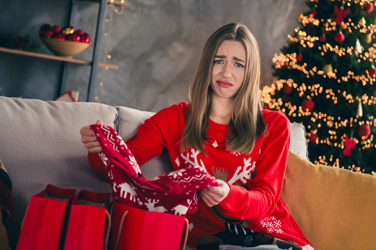 Photo of young girl dislike sweater shopping bags wear red christmas clothes enjoy modern cozy x-mas party decoration interior flat indoors