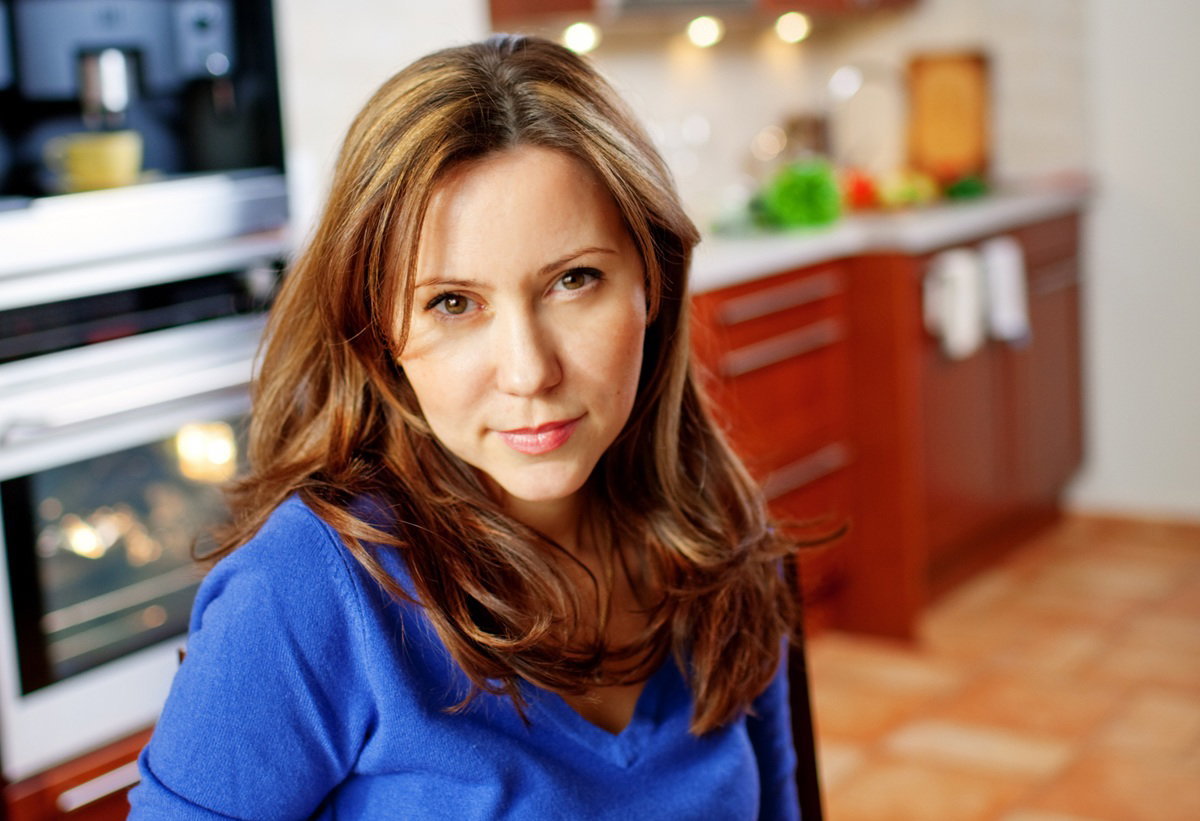 kobieta w wieku 35 plus w niebieskim sweterku siedzi w kuchni zamyślona