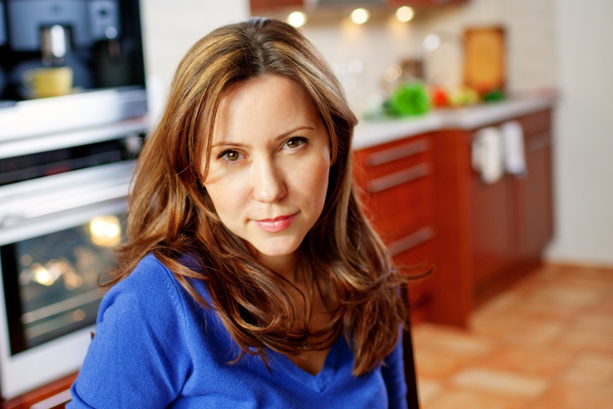 kobieta w wieku 35 plus w niebieskim sweterku siedzi w kuchni zamyślona