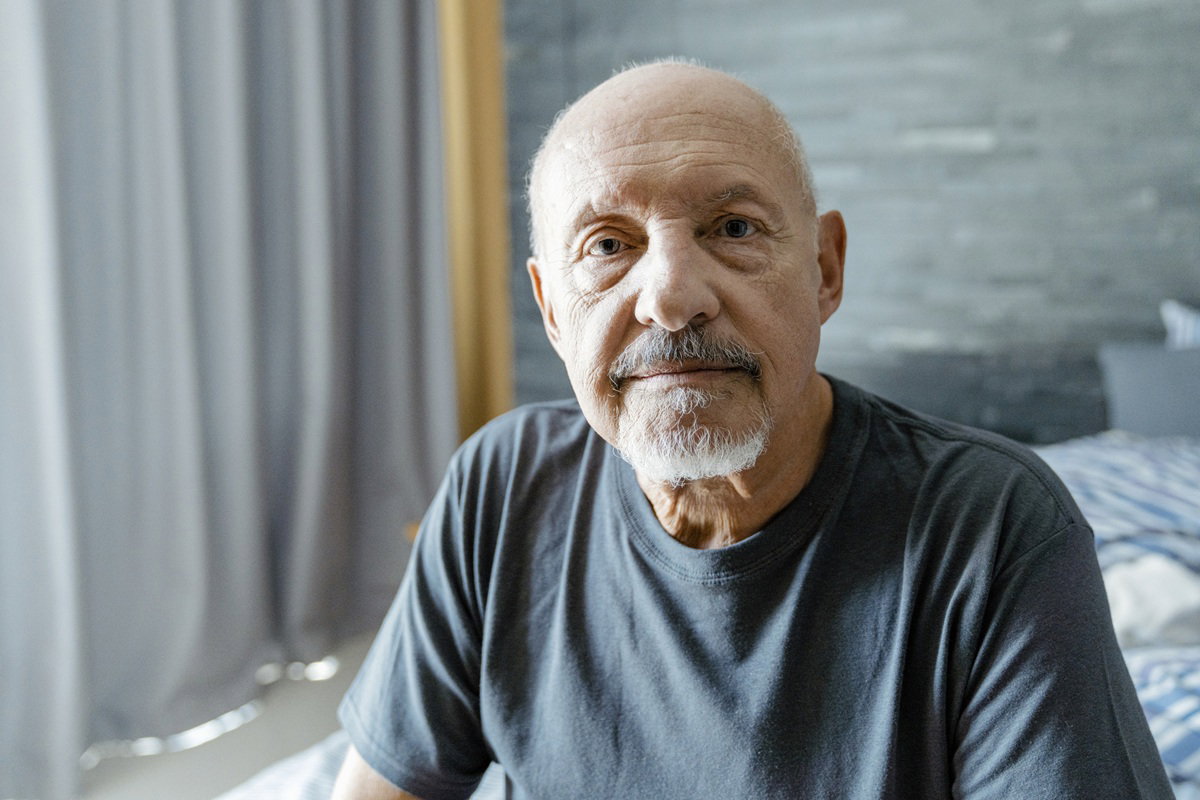 mężczyzna w wieku 71 lat siedzi na łóżku zmartwiony
