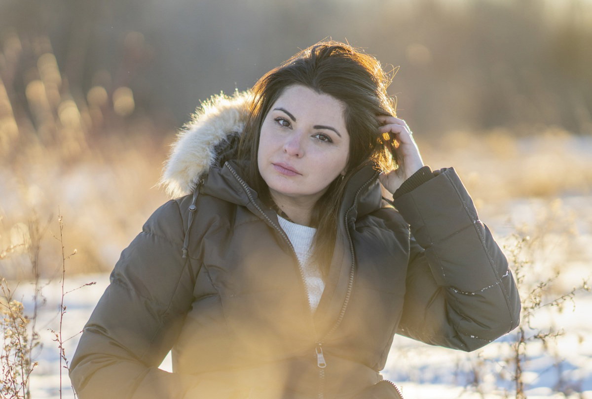 kobieta w wieku 35 lat siedzi smutna w kurtce na zewnątrz na tle zaśnieżonego pejzażu