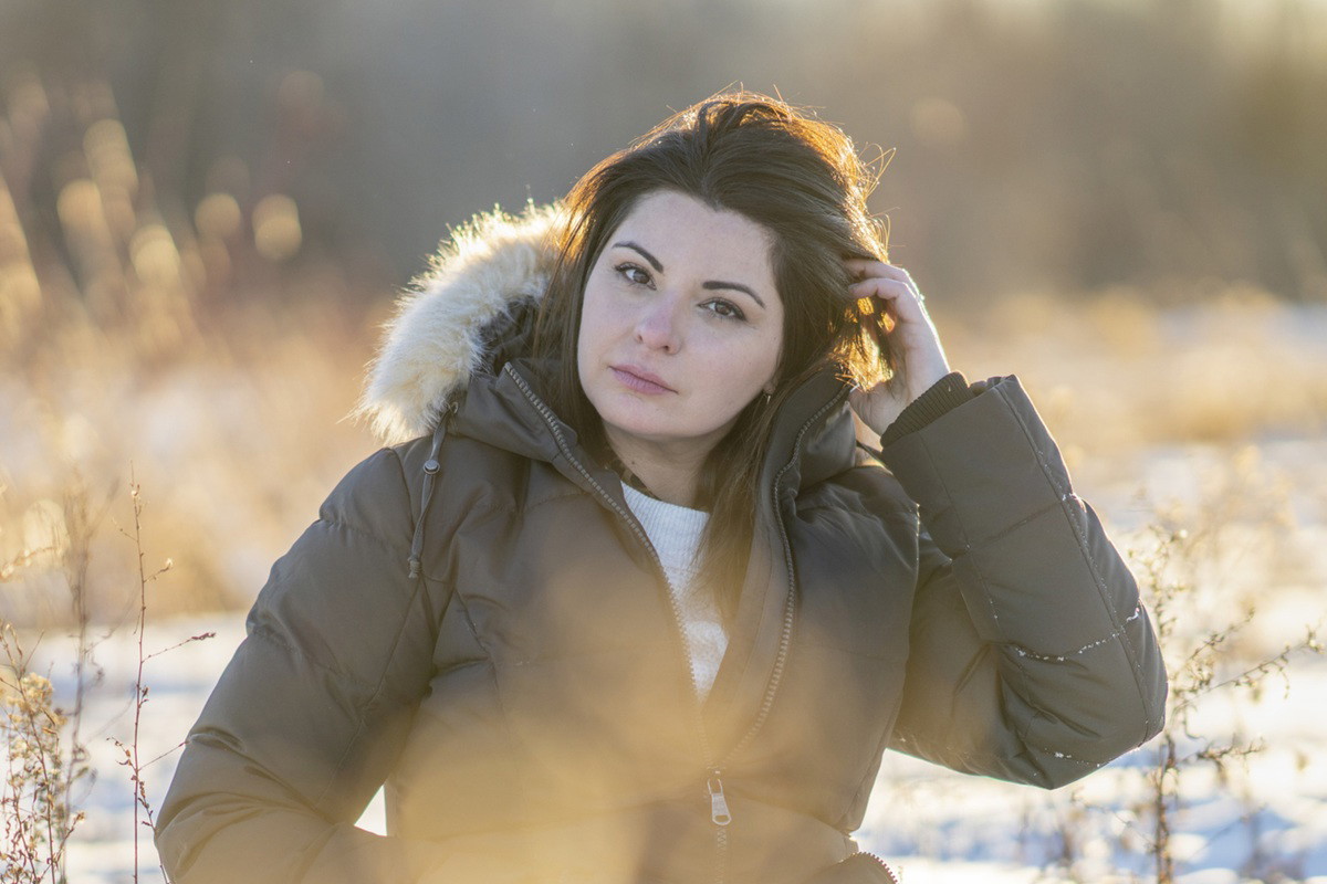 kobieta w wieku 35 lat siedzi smutna w kurtce na zewnątrz na tle zaśnieżonego pejzażu