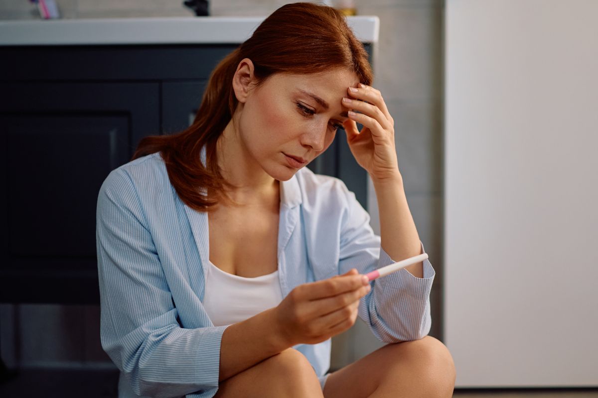 Załamana kobieta z testem ciążowym