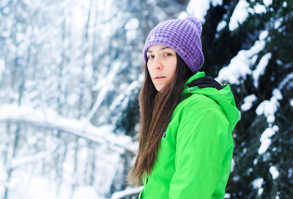 kobieta w wieku 30 plus w jaskrawej kurtce i czapce stoi smutna na tle zaśnieżonego pejzażu