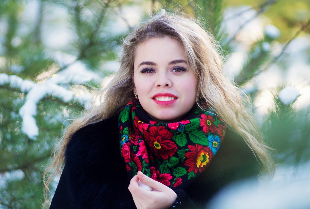 dziewczyna 25 plus w kolorowej chuście folkowej z długimi włosami stoi rozpromieniona na dworze