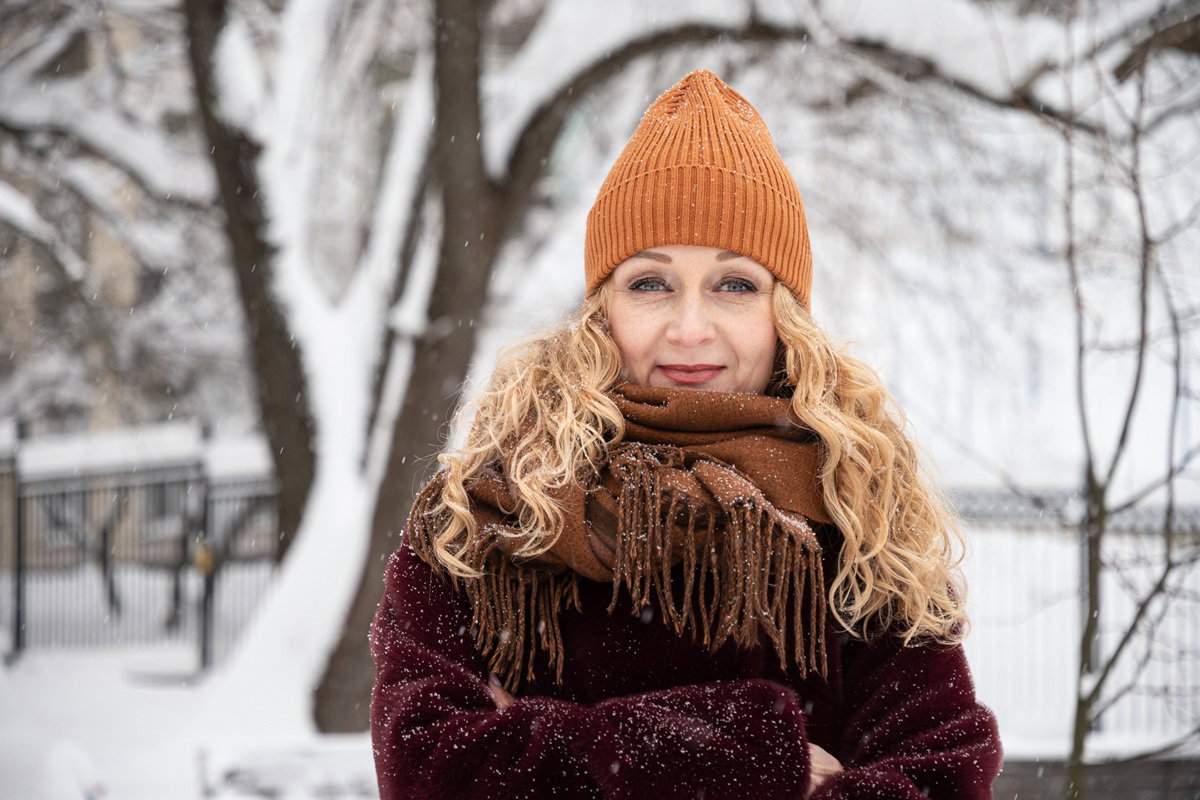 kobieta w wieku 40 plus w pomarańczowej czapce stoi na tle zimowej przestrzeni