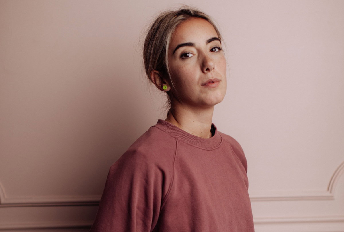 kobieta w wieku około 30 lat w bluzie blondynka stoi na tle ściany z wkurzonym wyrazem twarzy