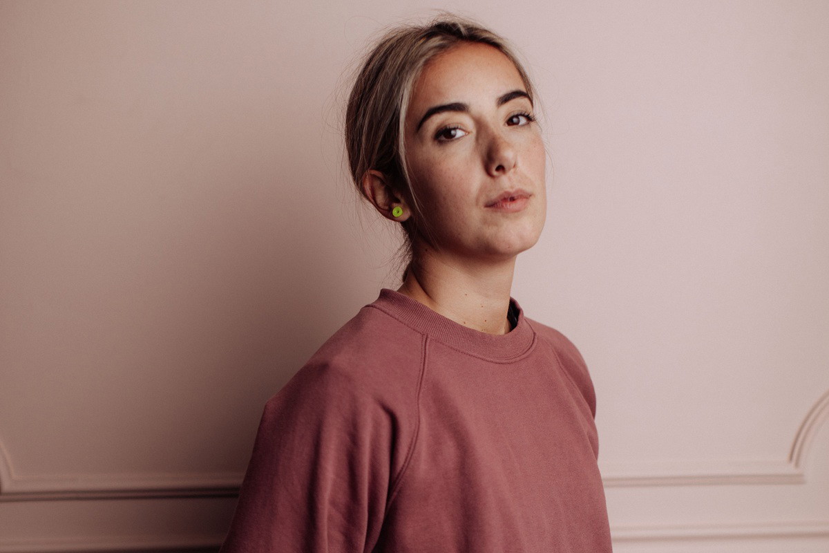 kobieta w wieku około 30 lat w bluzie blondynka stoi na tle ściany z wkurzonym wyrazem twarzy