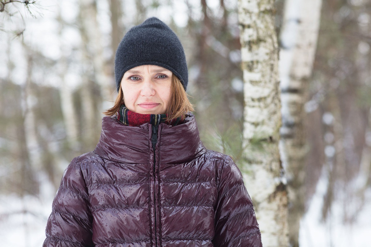 kobieta w wieku 35 plus w burgundowej kurtce stoi zmartwiona na zewnątrz