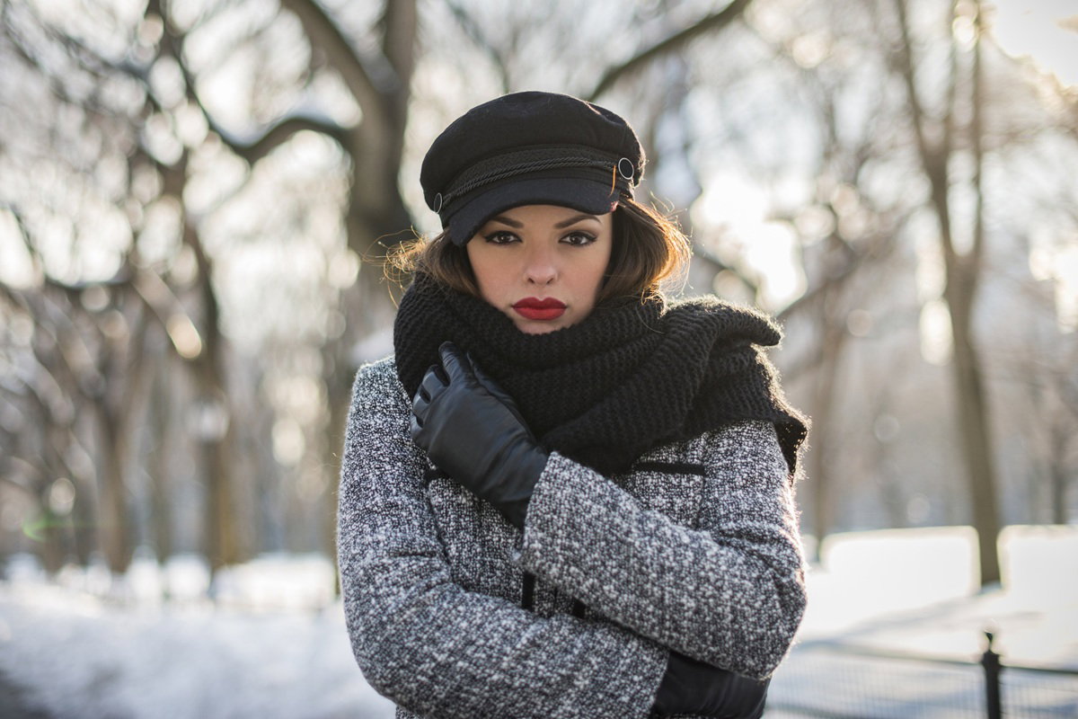 kobieta w wieku około 30 lat w kaszkiecie i płaszczu stoi na zewnątrz zamyślona i smutna