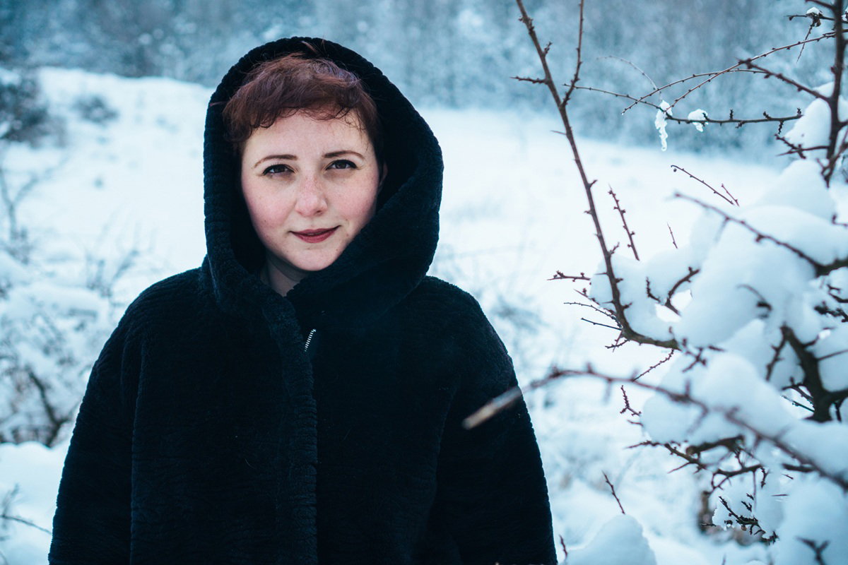 kobieta w wieku 35 plus w czarnym płaszczu na tle zimowego pejzażu