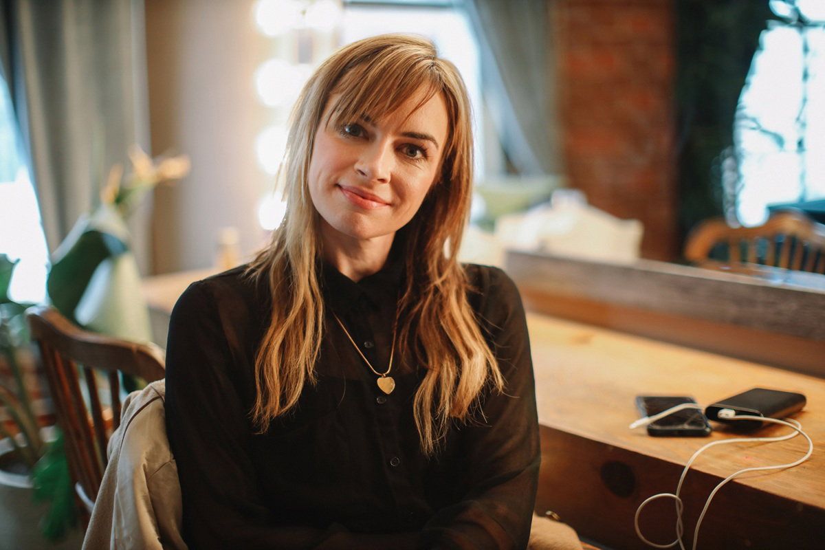 kobieta w wieku 35 plus w czarnej bluzce siedzi uśmiechnięta i zadowolona