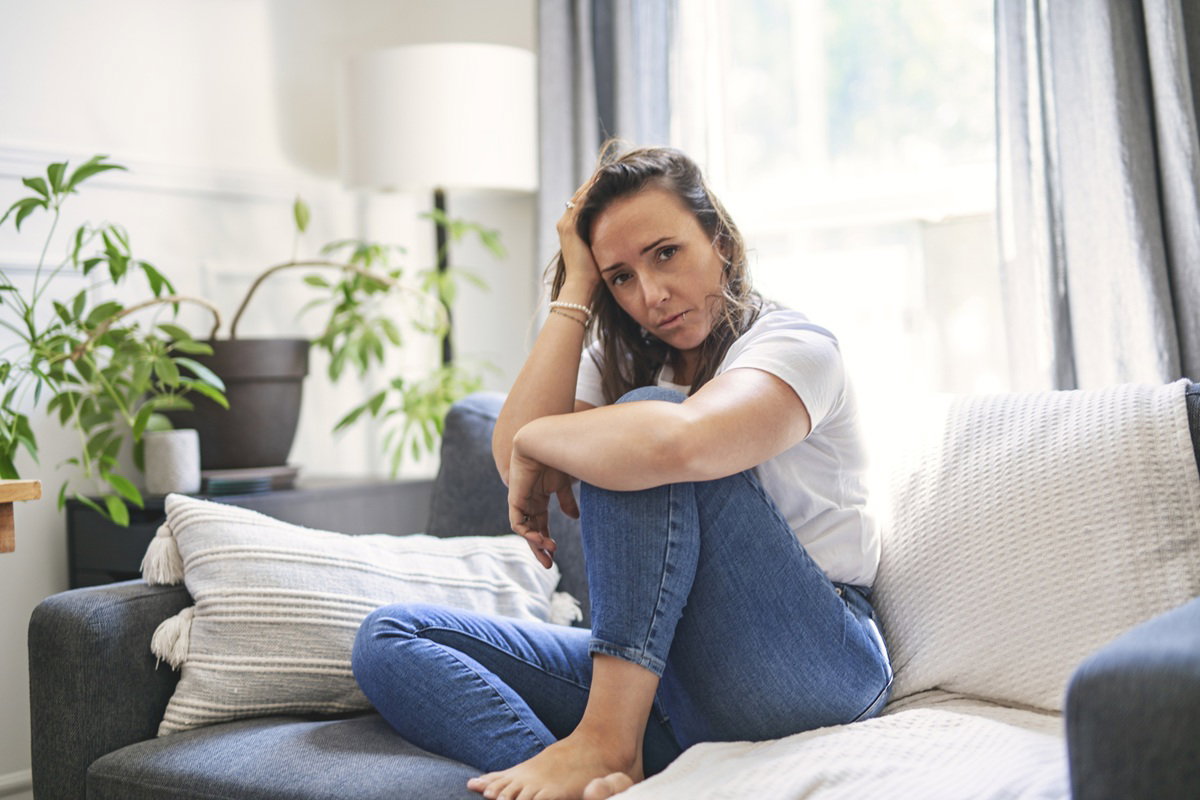 kobieta w wieku 35 plus siedzi na kanapie smutna i załamana