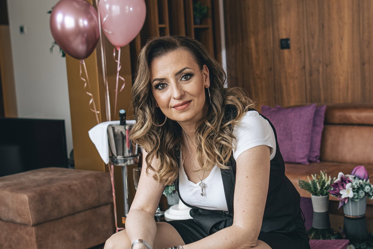 kobieta w wieku 40 plus siedzi z balonikami w salonie i uśmiecha się kpiąco