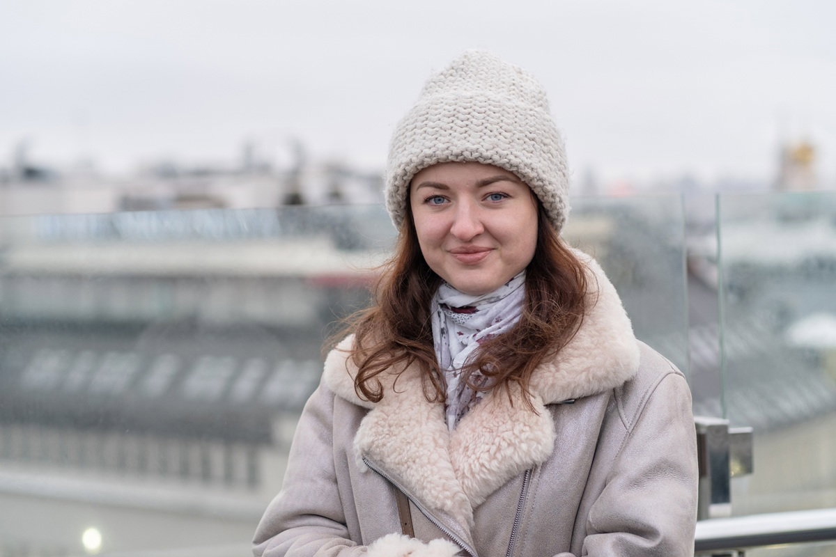 kobieta w wieku 35 plus w czapce stoi na zewnątrz miejskie tło i uśmiecha się z przekąsem