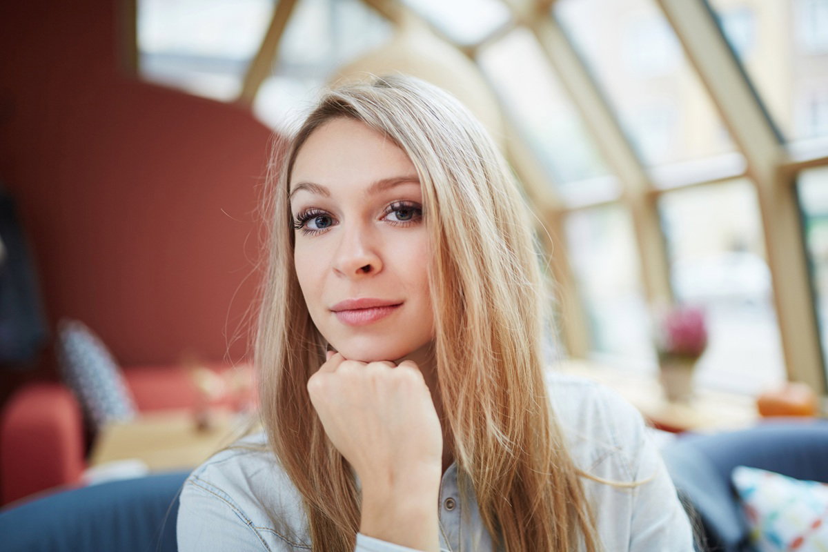 kobieta w wieku 25 plus blondynka siedzi podpierając brodę ręką zamyślona