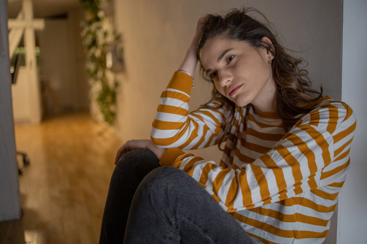 kobieta w wieku 30 plus w pasiastej bluzce siedzi na podłodze załamana