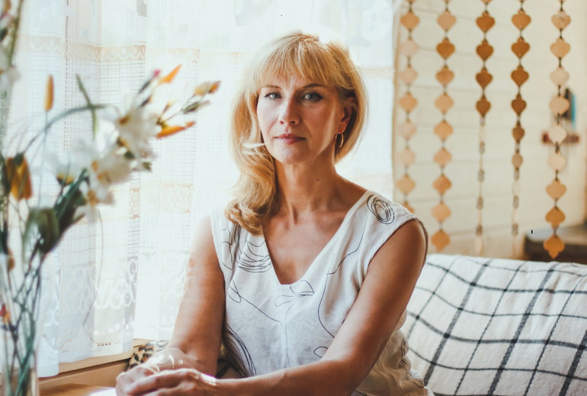 kobieta w wieku 40 plus blondynka siedzi z rękami na stole poważna