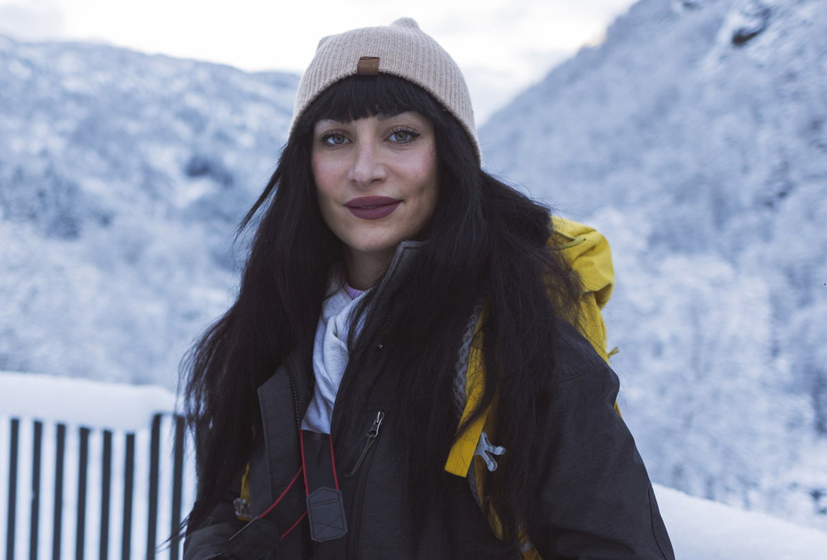 kobieta w wieku 25 plus w beżowej czapce na tle gór stoi z pewną siebie miną